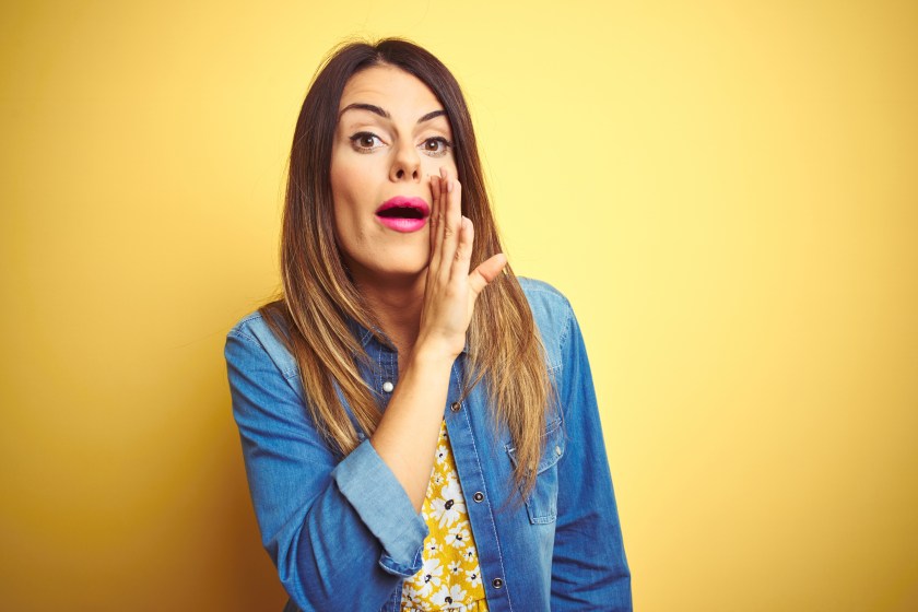 Young beautiful woman standing over yellow isolated background hand on mouth telling secret rumor, whispering malicious talk conversation